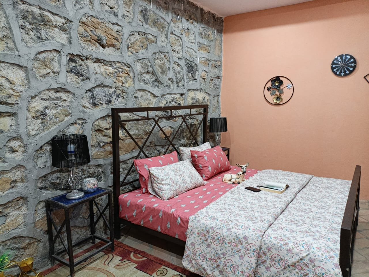 Cosy bedroom with stone wall, patterned linens and reading lamps
